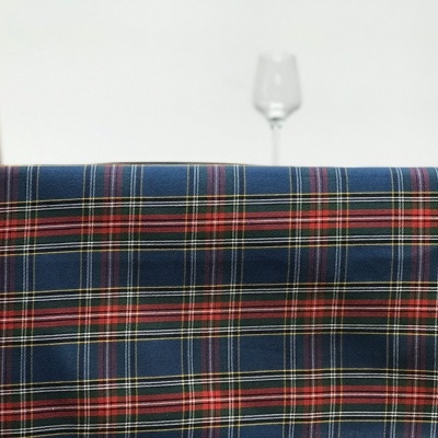 Toalha de mesa xadrez azul e vermelho com cadeira de madeira e taça de vidro ao fundo