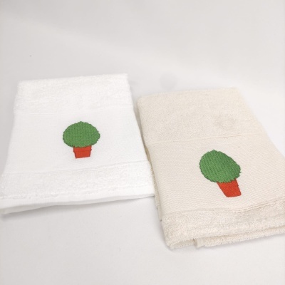Duas toalhas branco e bege com bordado de vaso de planta verde