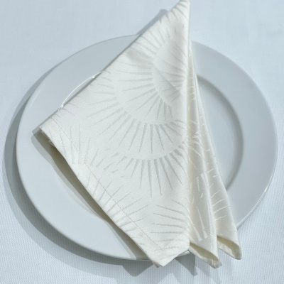 Guardanapo branco com padrão sobre prato branco numa mesa branca