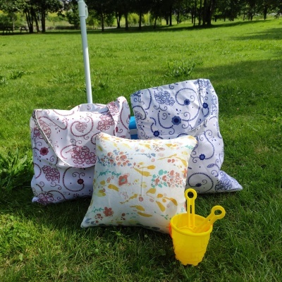 Três almofadas estampadas e balde amarelo em relva verde ao ar livre