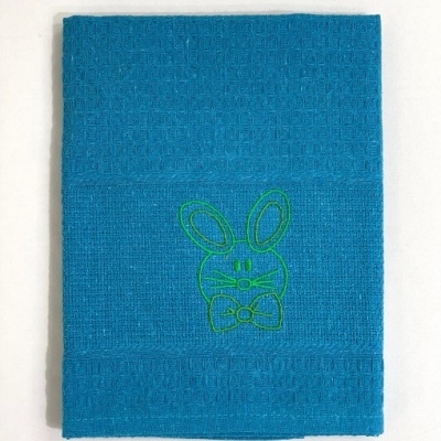 Toalha azul com bordado de coelho verde em fundo branco