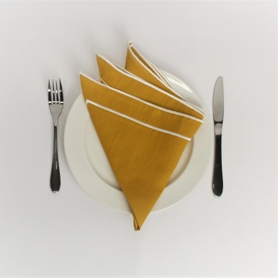 Prato branco com guardanapo amarelo mostarda e talheres de metal