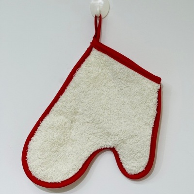 Luvas de forno branca felpuda com bordas vermelhas penduradas numa parede branca