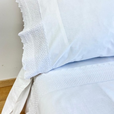 Fronha e lençol brancos com textura waffle e renda em cama