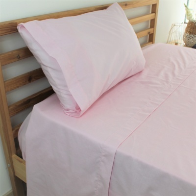 Jogo de cama rosa claro numa cama de madeira clara