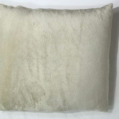 Almofada bege claro aveludada sobre superfície branca