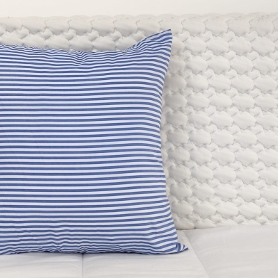 Almofada azul às riscas brancas sobre sofá branco texturizado