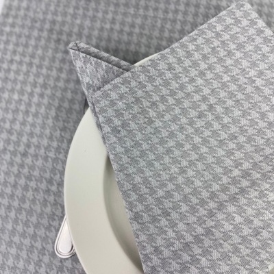 Guardanapo e toalha de mesa cinzentos com padrão pied-de-poule sobre prato branco