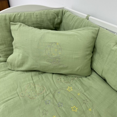 Conjunto de berço verde com bordados de estrelas e nuvens