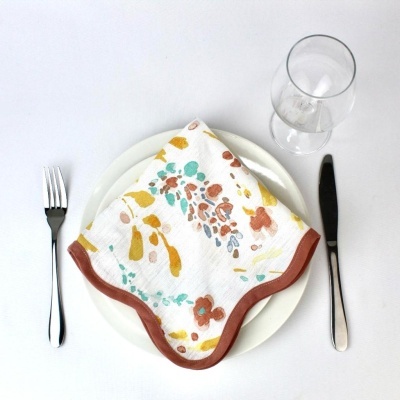 Mesa posta com prato branco, guardanapo floral, talheres e copo transparente