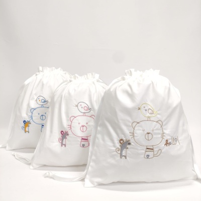 Sacos de tecido branco com bordados de ursinho, pássaro e esquilo em azul, rosa e bege.