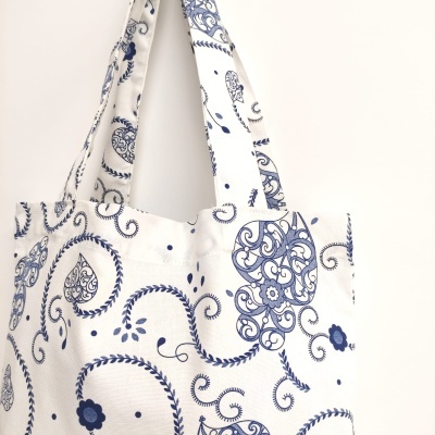 Saco de tecido branco com padrão azul floral e arabescos