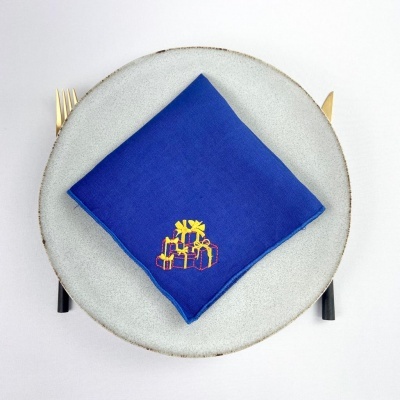 Guardanapo azul bordado sobre prato cinza com talheres