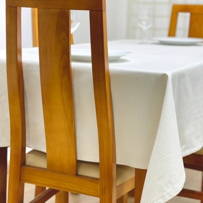 Cadeira de madeira clara com toalha branca numa mesa interior