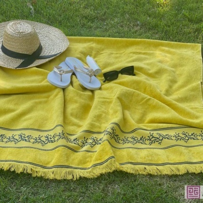 Toalha amarela com padrões florais na relva com chapéu, chinelos e óculos de sol