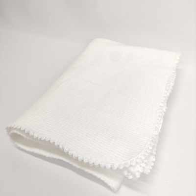 Toalha branca com borda de pompons sobre fundo branco