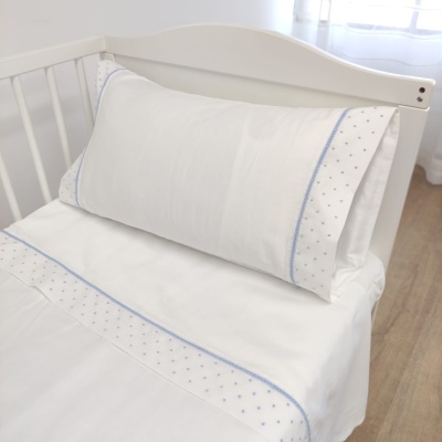 Travesseiro e lençol brancos com bordado azul numa cama branca