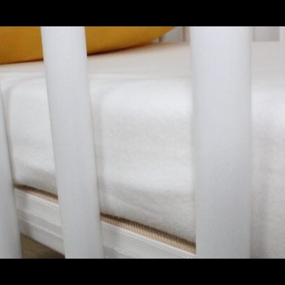 Berço infantil branco com colchão e almofada amarela.