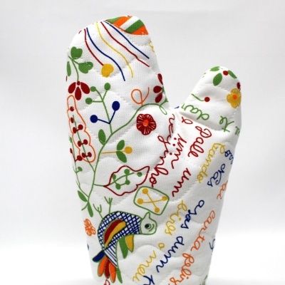 luva de forno branca com padrão colorido de plantas, flores e texto