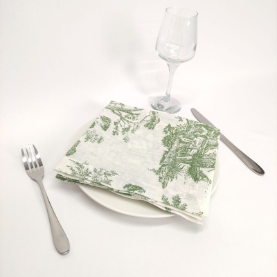 Conjunto de mesa com prato branco, guardanapo estampado verde, talheres em inox e copo de vinho