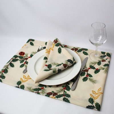 Mesa posta com prato branco, talheres, copo e guardanapo estampado de folhas verdes e bagas