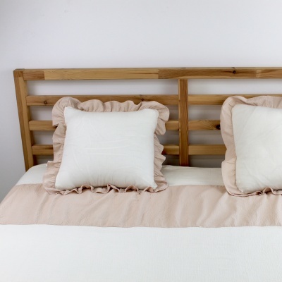 Cama com cabeceira de madeira clara e almofadas brancas com bordas bege