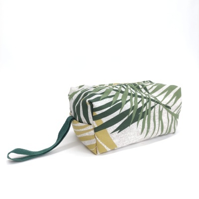 Necessaire com padrão de folhas verdes e amarelas e alça verde escura