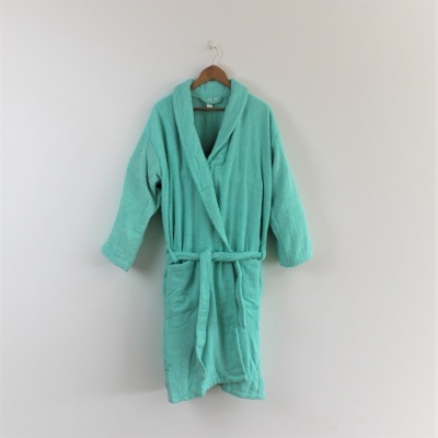 Robe de banho verde água pendurado em cabide de madeira