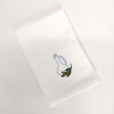 Toalha branca com bordado de garrafa de vidro azul e folhas verdes