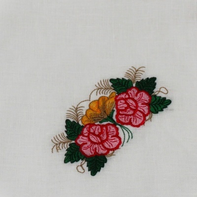 Tecido branco com bordado floral em cores rosa, amarelo, verde e castanho