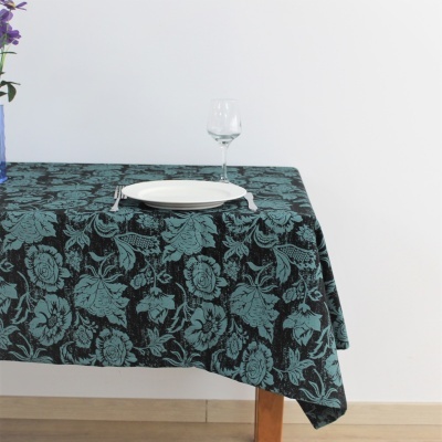 Toalha de mesa retangular com padrão floral verde e preto sobre mesa de madeira