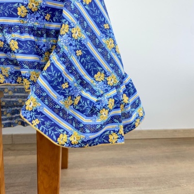 Toalha de mesa azul com flores amarelas e riscas brancas e azuis sobre mesa de madeira