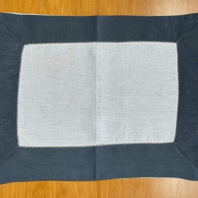 Toalhete retangular branco com borda cinza-escuro sobre superfície de madeira