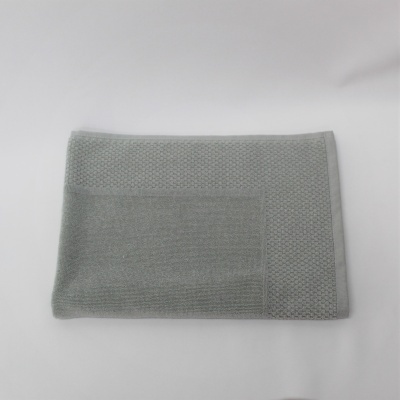 Toalha cinzenta com padrão de losangos e secção lisa