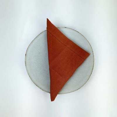 Prato cinza claro com guardanapo laranja dobrado ao centro