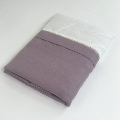 Toalha de banho dupla cor branca e lilás dobrada sobre fundo branco.