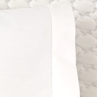 Almofada branca com costura decorativa sobre superfície acolchoada branca