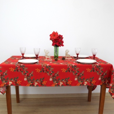 Mesa posta com toalha vermelha decorativa, pratos, copos e centro de mesa com flores e decorações natalinas