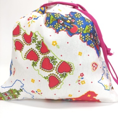 Saco de tecido branco com padrão colorido de corações, flores e cordão cor de rosa