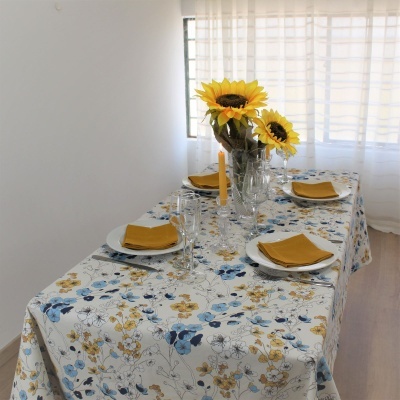 Mesa de jantar com toalha floral e guardanapos amarelos em sala iluminada