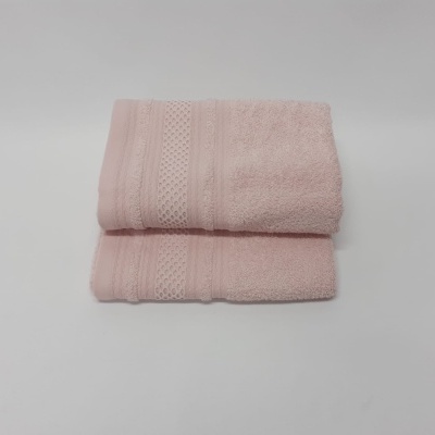 Toalhas de banho rosa claro dobradas com padrões texturizados em fundo branco