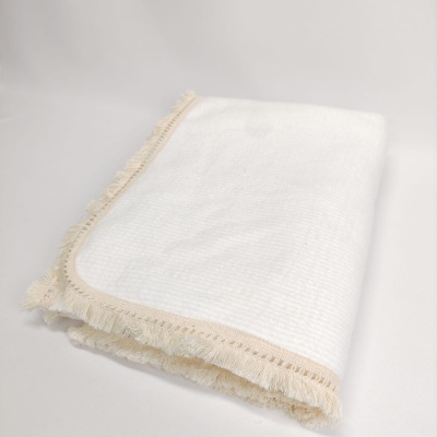 Toalha branca com franjas decorativas creme dobrada