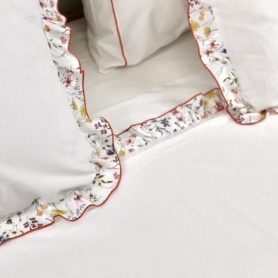 Lençóis brancos com bainha floral colorida e contorno laranja