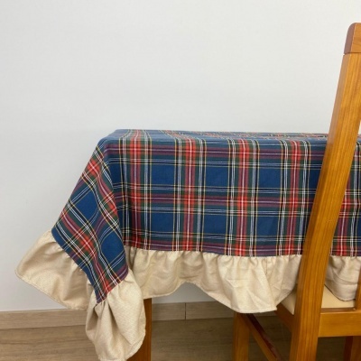 Toalha de mesa xadrez azul com barra bege sobre mesa de madeira e cadeiras.