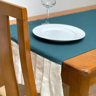 Mesa de madeira com toalha verde e prato branco com taça