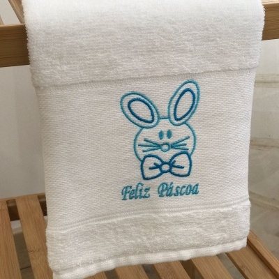 Toalha branca com bordado azul de coelho e texto FELIZ PÁSCOA