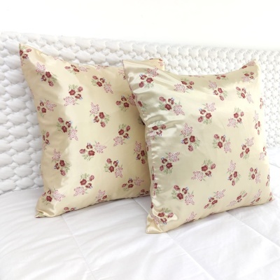 Duas almofadas amarelas com flores rosas sobre roupa de cama branca