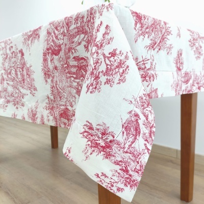 Toalha de mesa branca com padrão vermelho pendendo de mesa de madeira