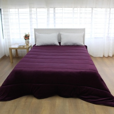 Colcha roxa escura acolchoada na cama em quarto com decoração clara e minimalista
