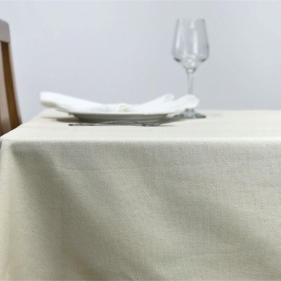 Mesa com toalha bege, cadeira de madeira e taça transparente